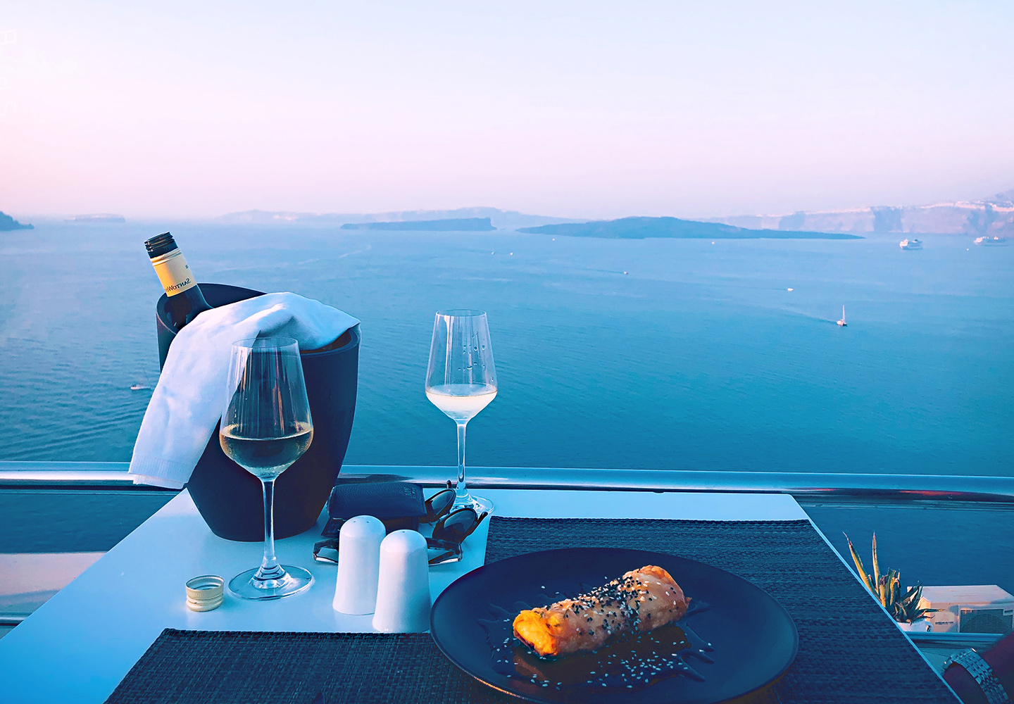 bottle of wine and glass facing blue ocean