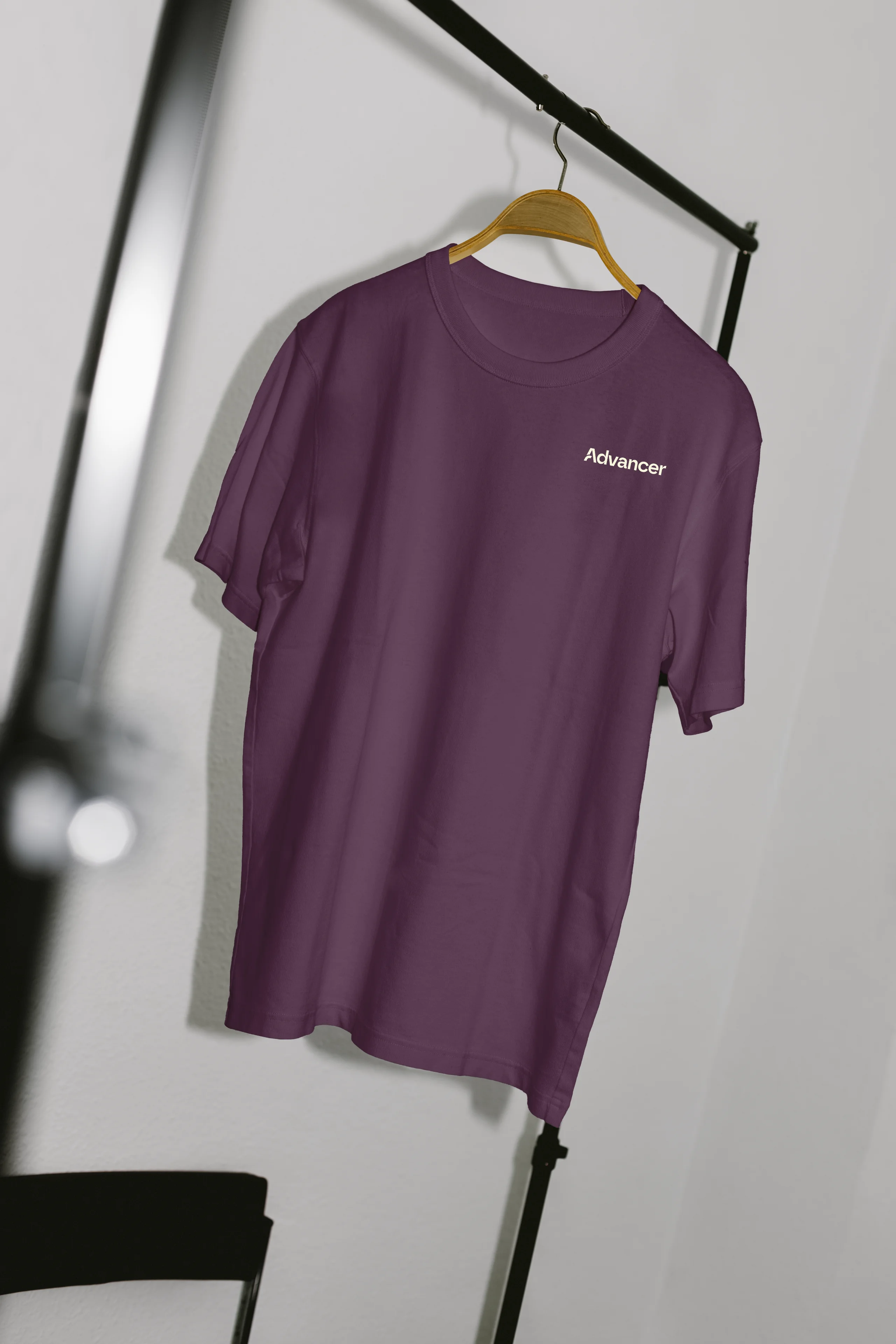 Purple T-shirt on wooden hanger with the word 'Advancer' printed on the upper left chest.