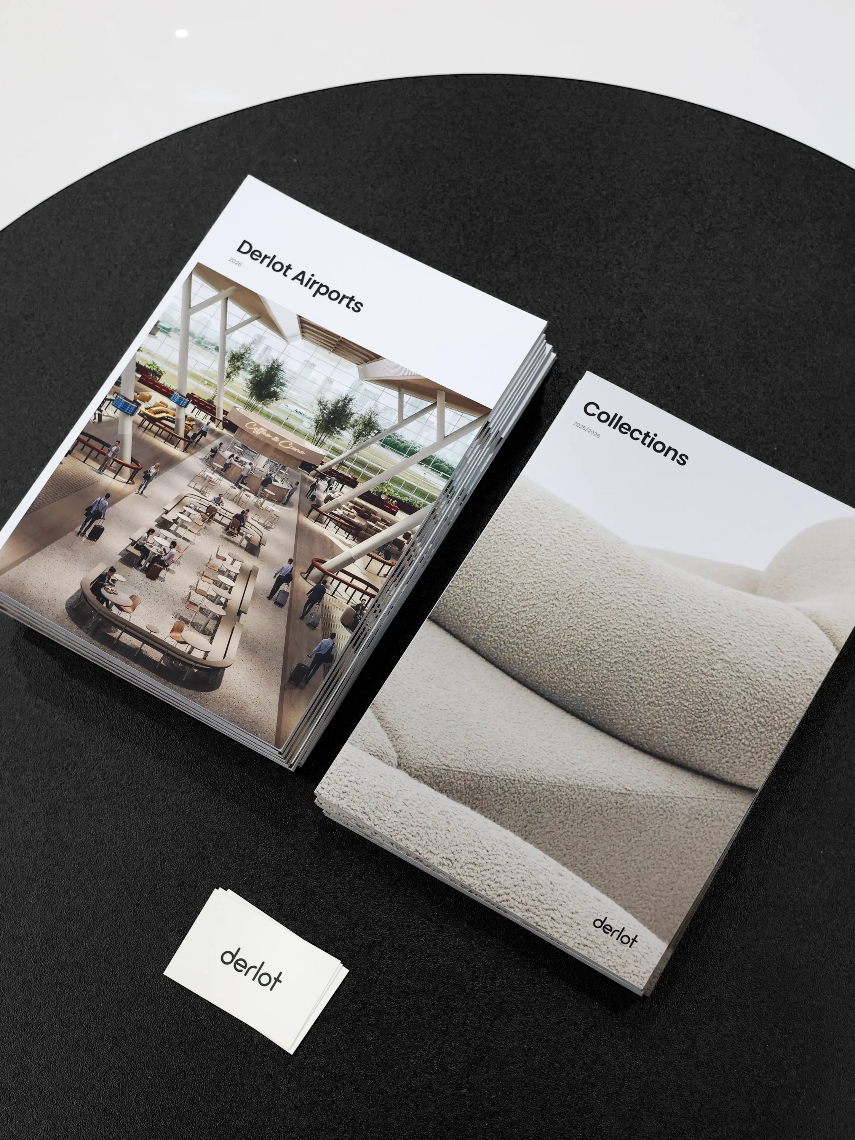 Stacks of brochures titled 'Derlot Airports' and 'Collections' on a black surface with a small Derlot logo card.