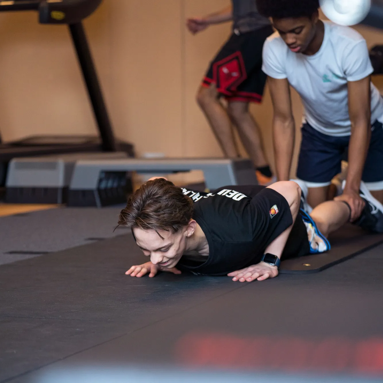 Jonge sporter doet een oefening op de mat onder begeleiding van een trainer