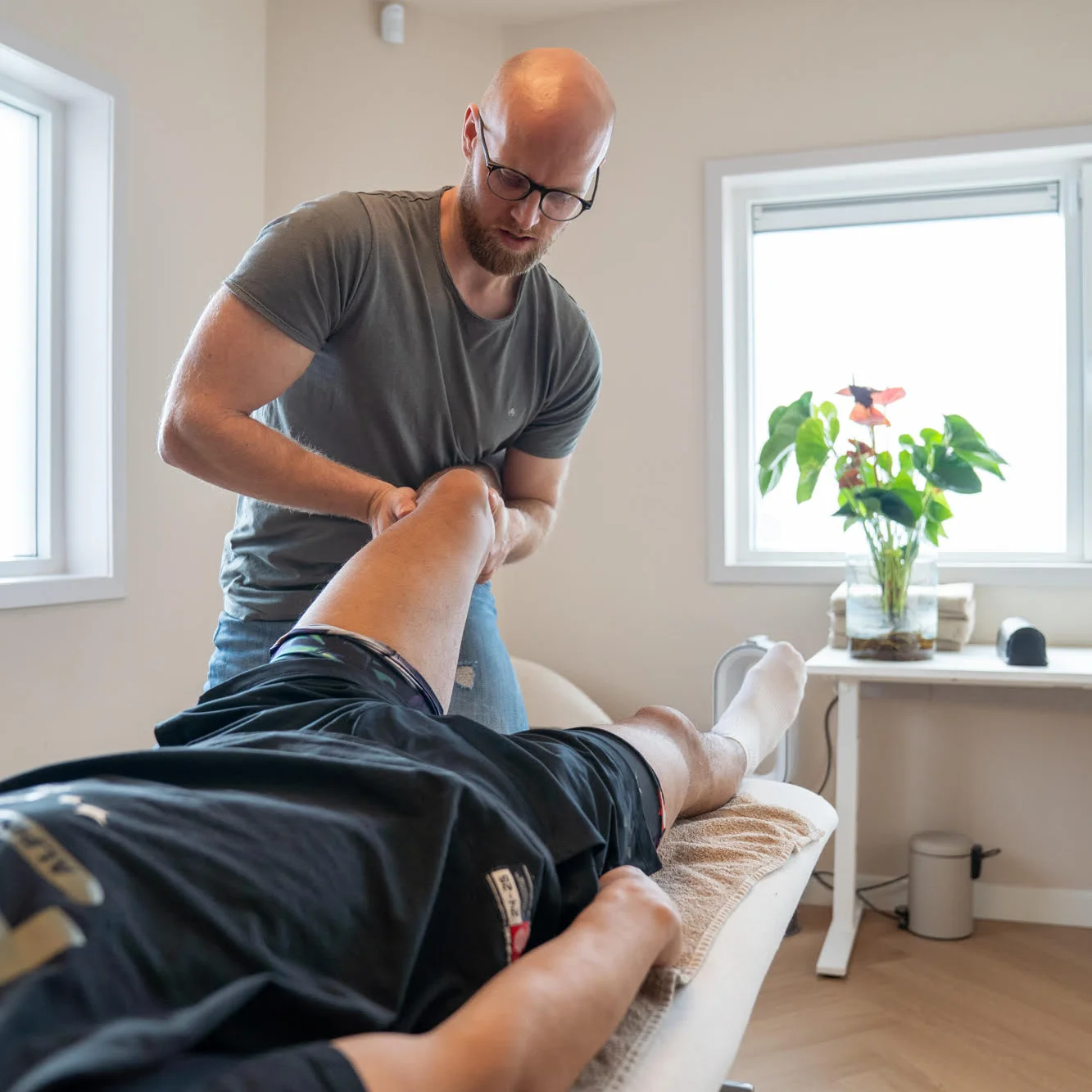 Roald onderzoekt de knie van een patiënt in de behandelkamer