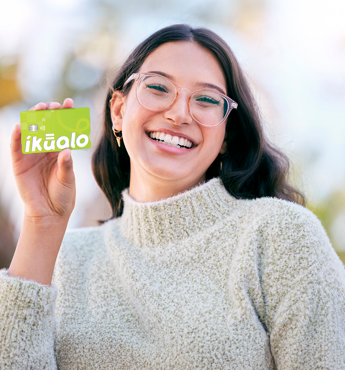 A happy young woman holding up a credit card