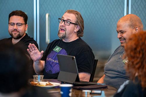 A person laughs at the camera in a group setting with a group of people.