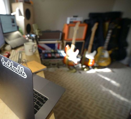 Home office with laptop and guitars in the background