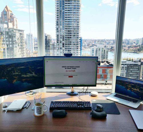 Home office with computer in front of a window with a view of a city landscape