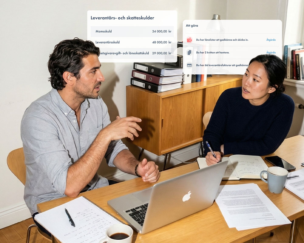 Två företagare går igenom bokföringen tillsammans vid en laptop, med överblick över leverantörsskulder, momsskuld och åtgärdslista i Bolageriets tjänst.