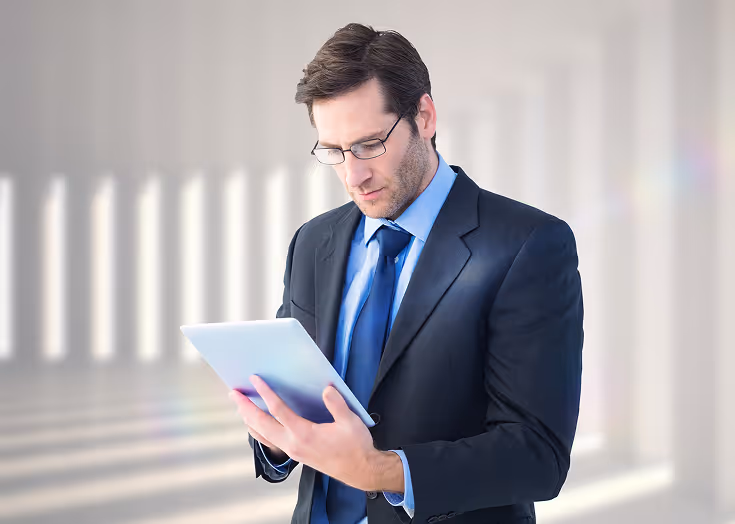 A man in a suit and tie holding a tablet.