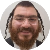 Smiling man with glasses, beard, and curly side hair wearing a dark suit and white shirt.