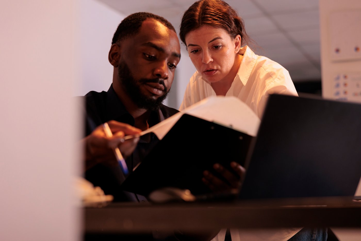 Zwei Personen schauen nachts im Büro gemeinsam auf Kennzahlen am Laptop