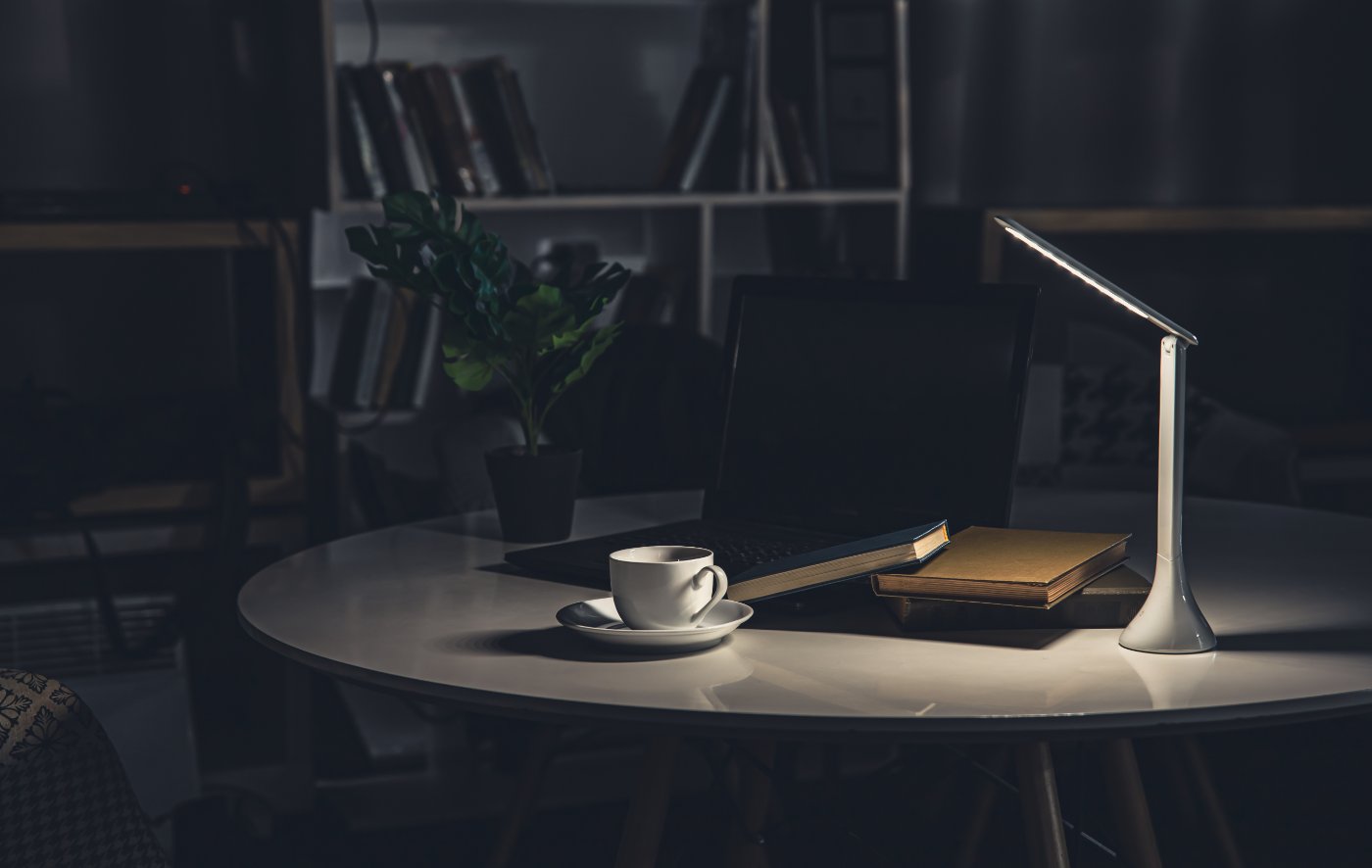 Aufgeräumter Schreibtisch mit Lampe und Notizen bei Nacht
