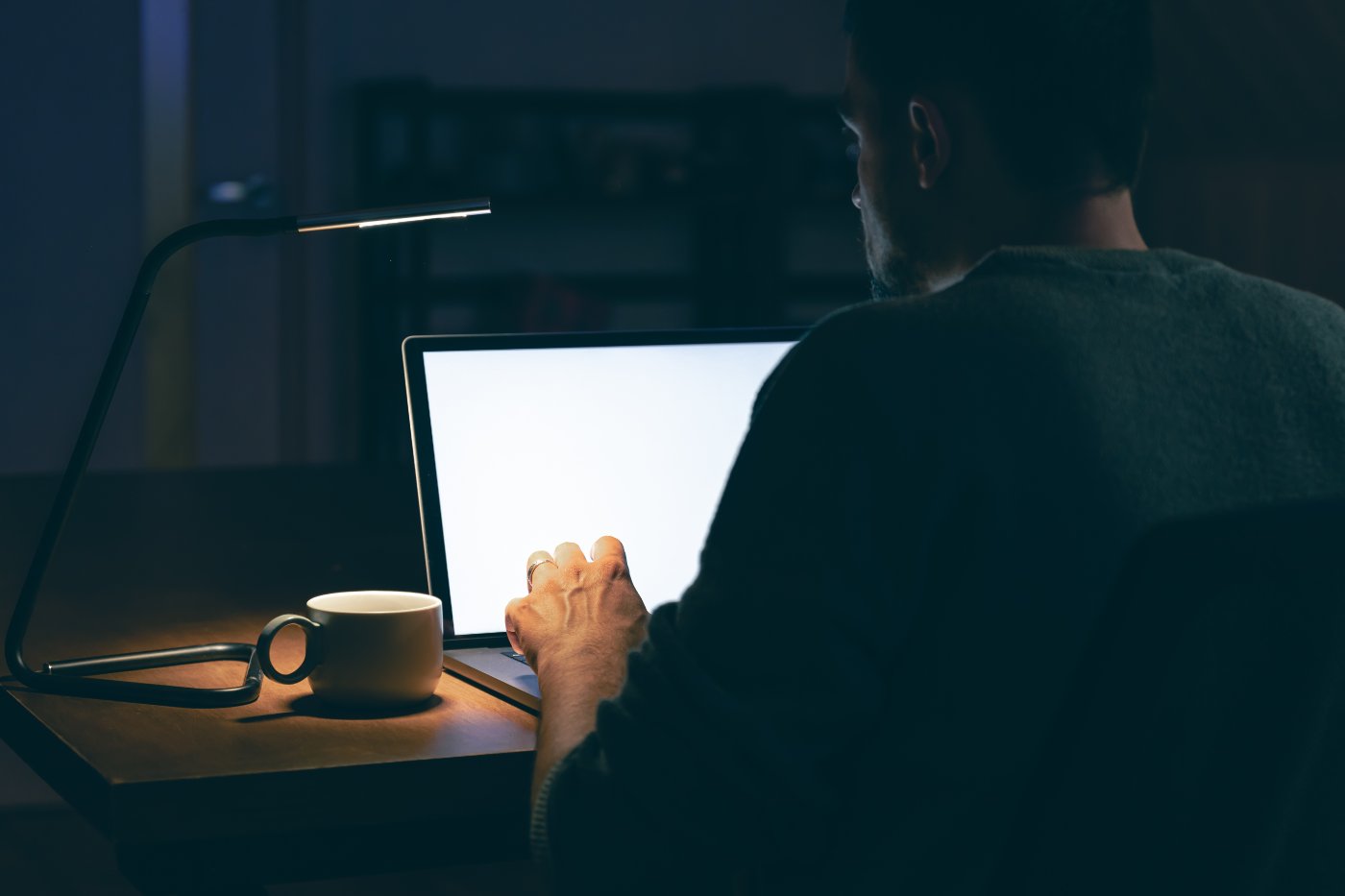 Person sitzt abends im dunklen Raum vor einem Laptop und strukturiert Inhalte