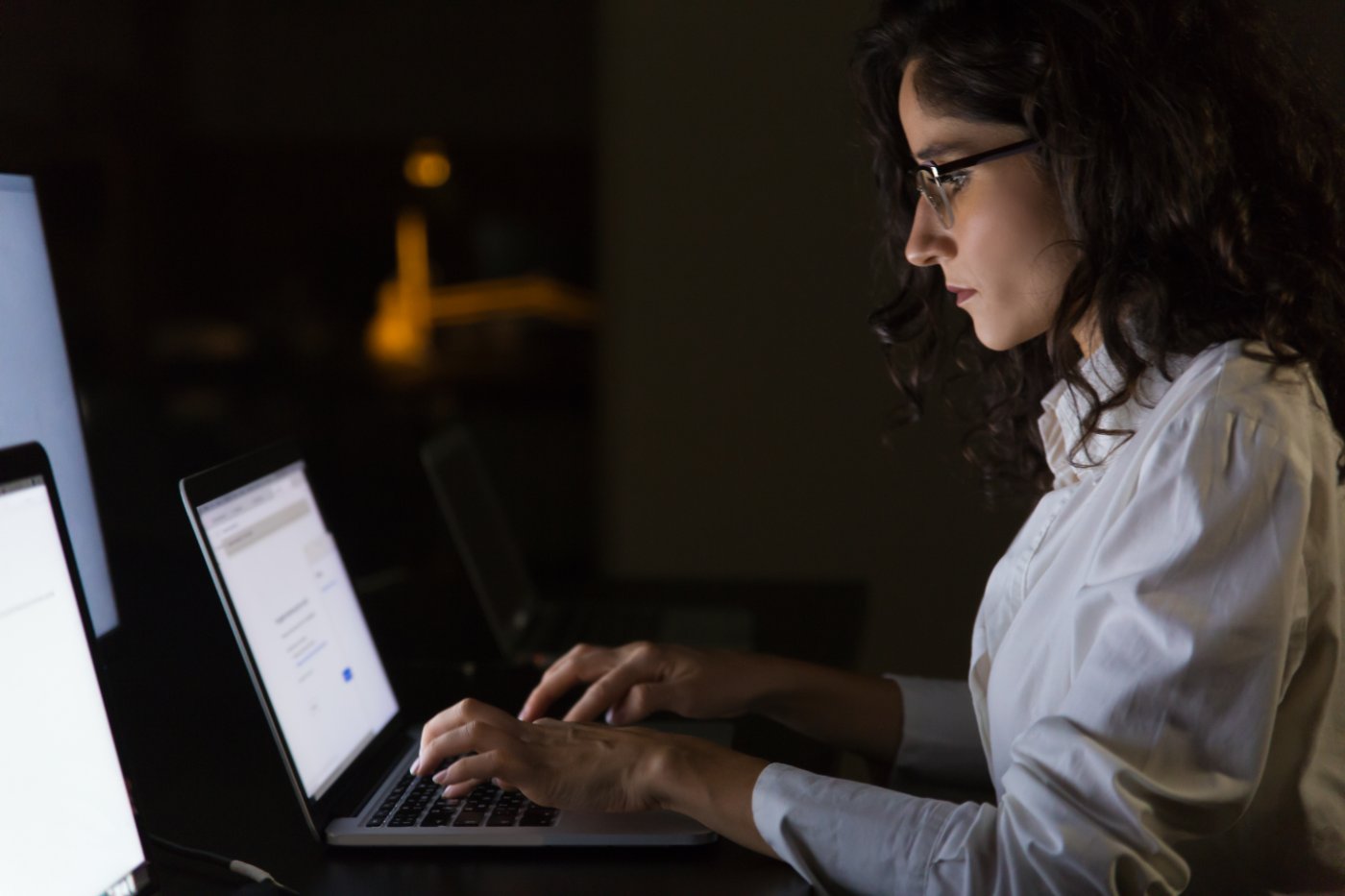 Person prüft abends im dunklen Büro einen Text am Laptop