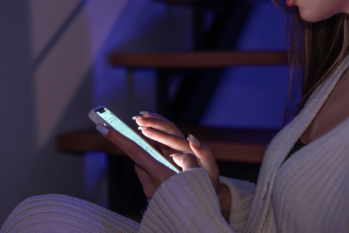 Hände halten abends ein Smartphone und scrollen durch eine Ergebnisliste