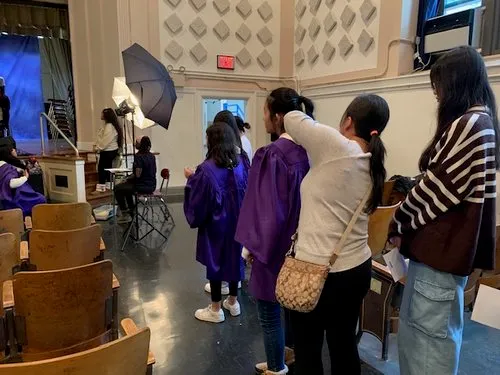 Students wait in line for photos in an auditorium with studio lighting set up.