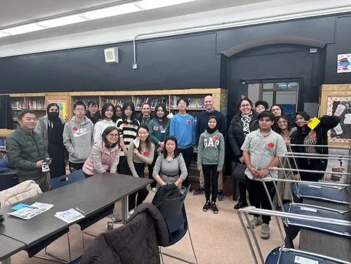 A group of students and teachers pose together in a classroom library.