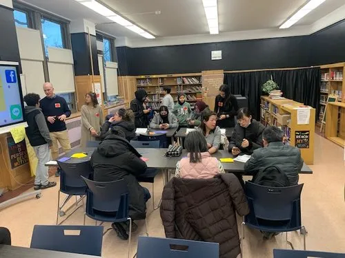 Students and teachers collaborate in small groups in a classroom library.