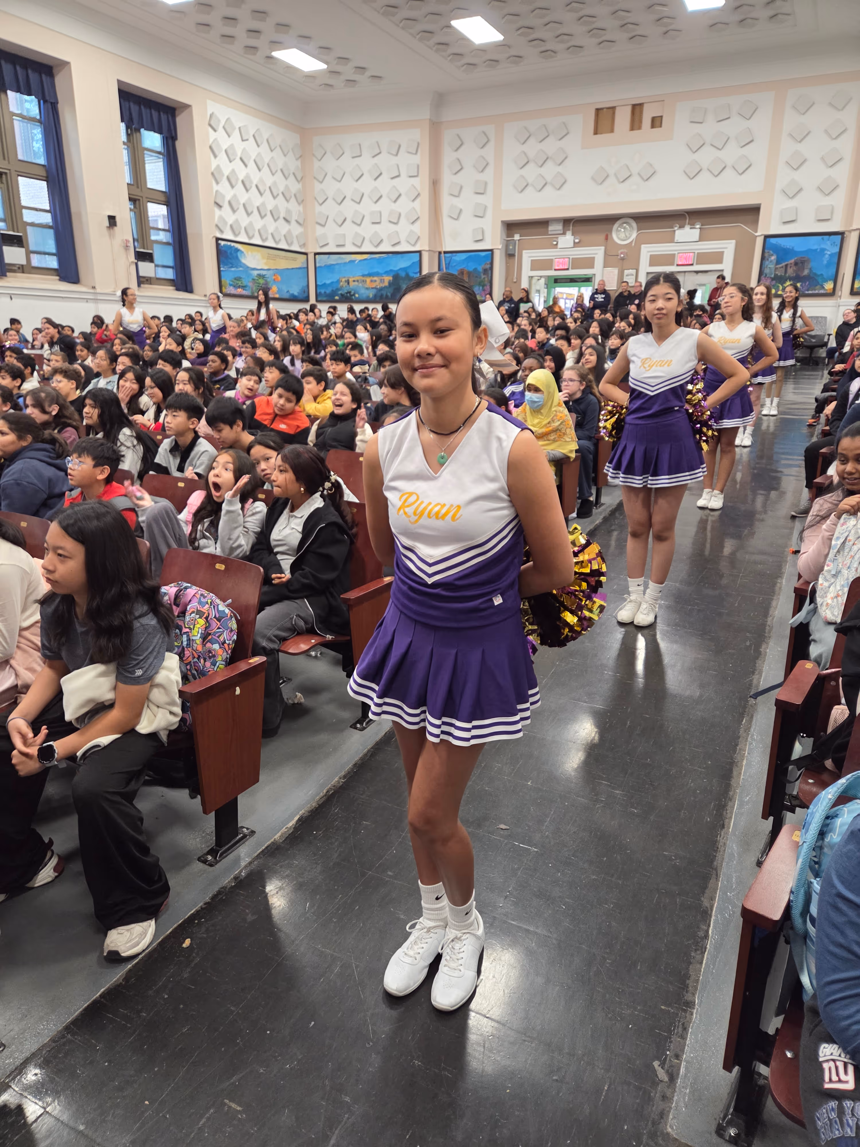 Cheerleader performing at school assembly in auditorium