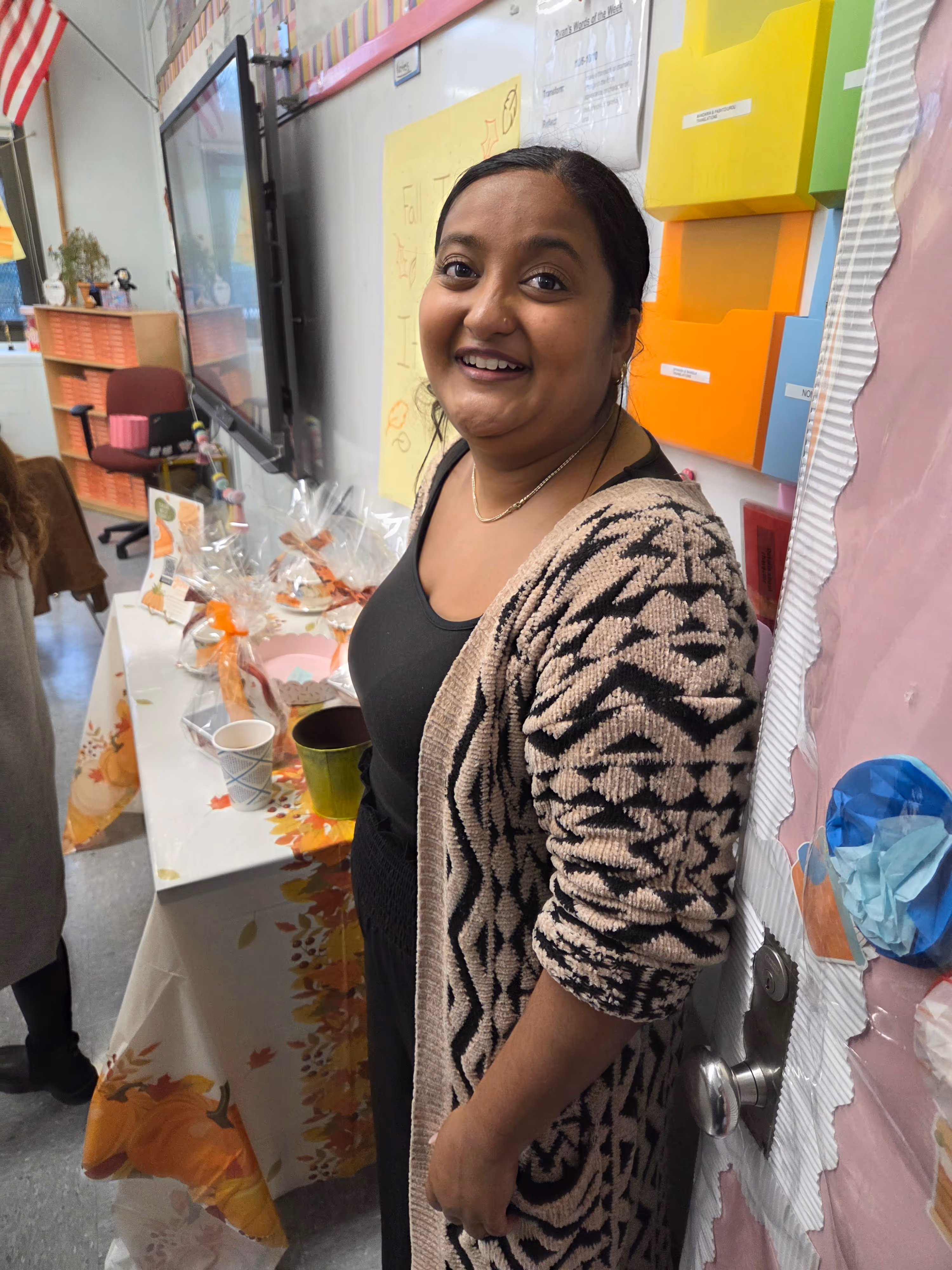 Teacher smiling in decorated classroom during fall celebration