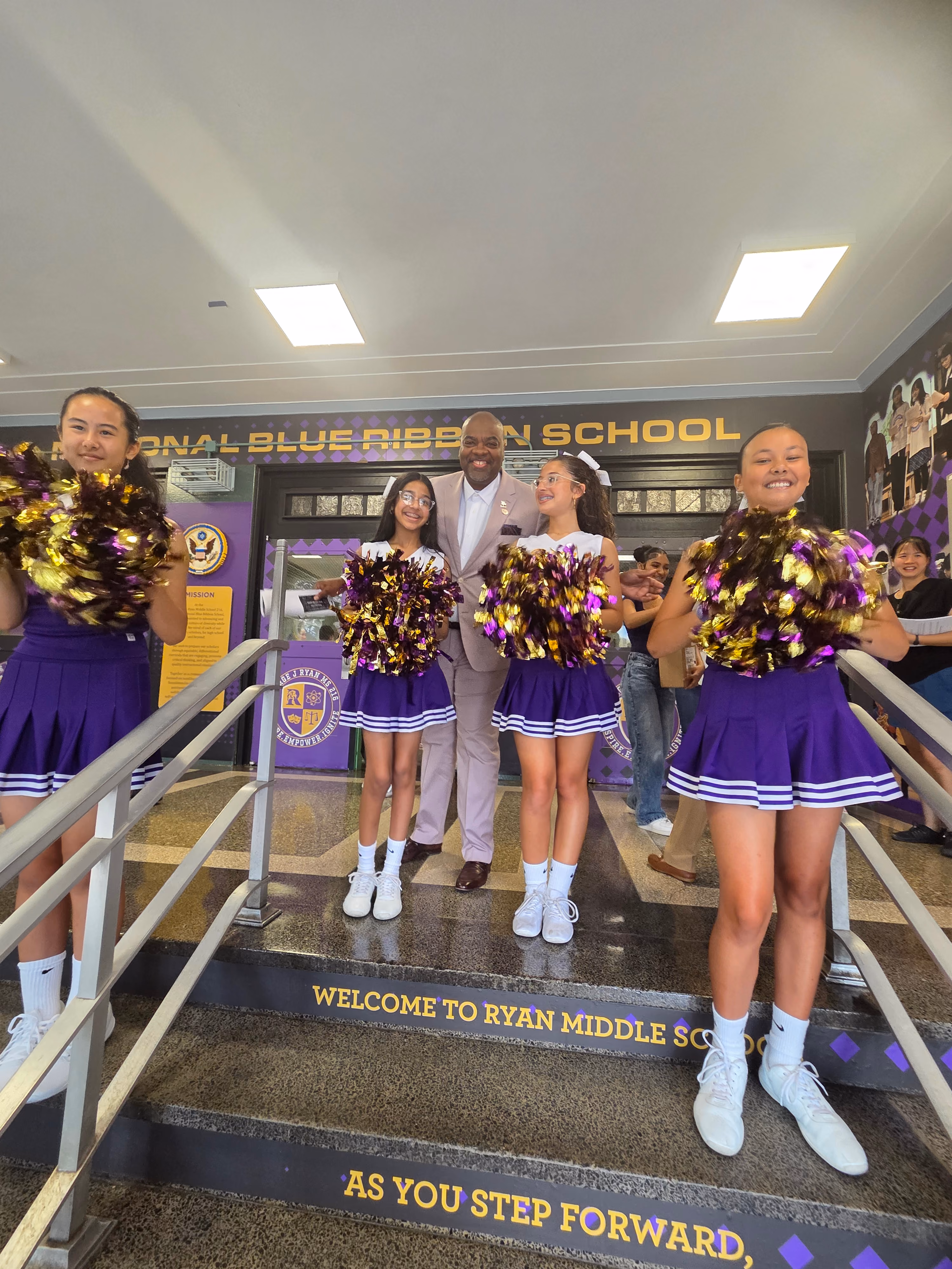 Cheerleaders in purple and gold uniforms with pom-poms