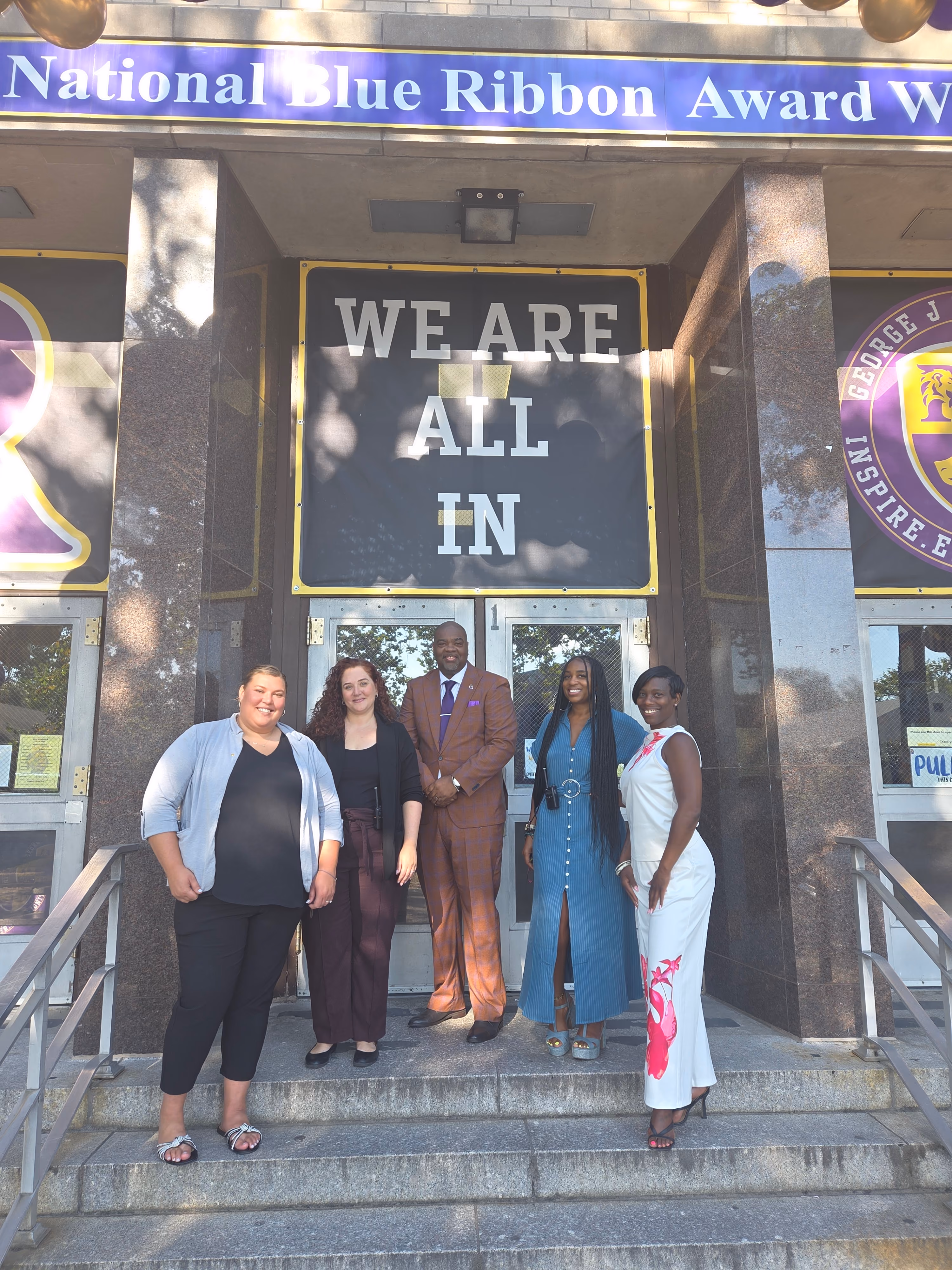Five staff members standing at school entrance