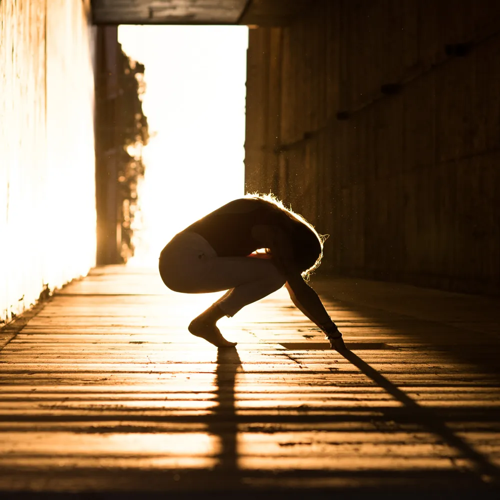 Janet in a crouching pose with bright sunlight behind her