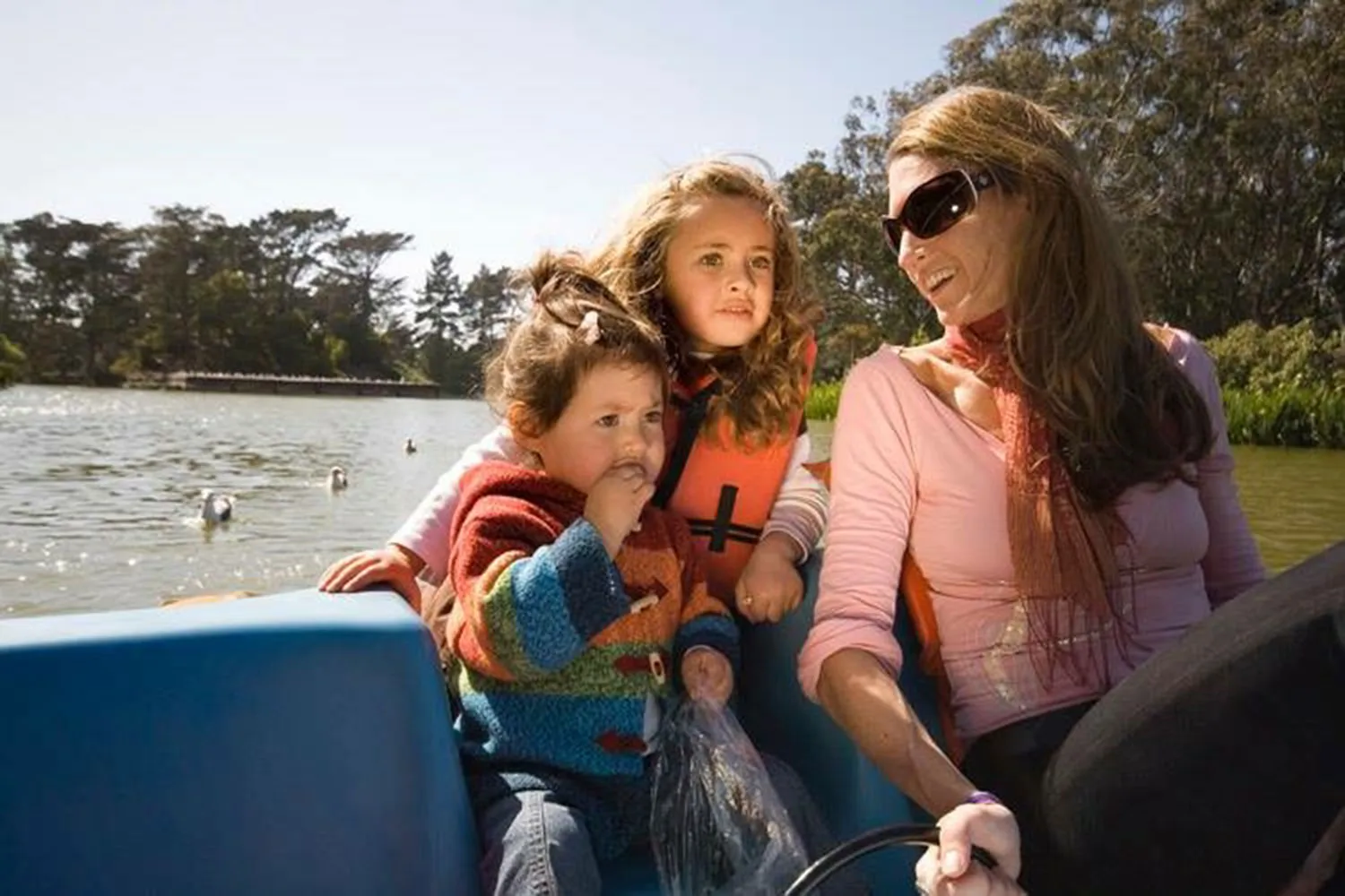Janet and her two young daughters on the water with ducks in the background