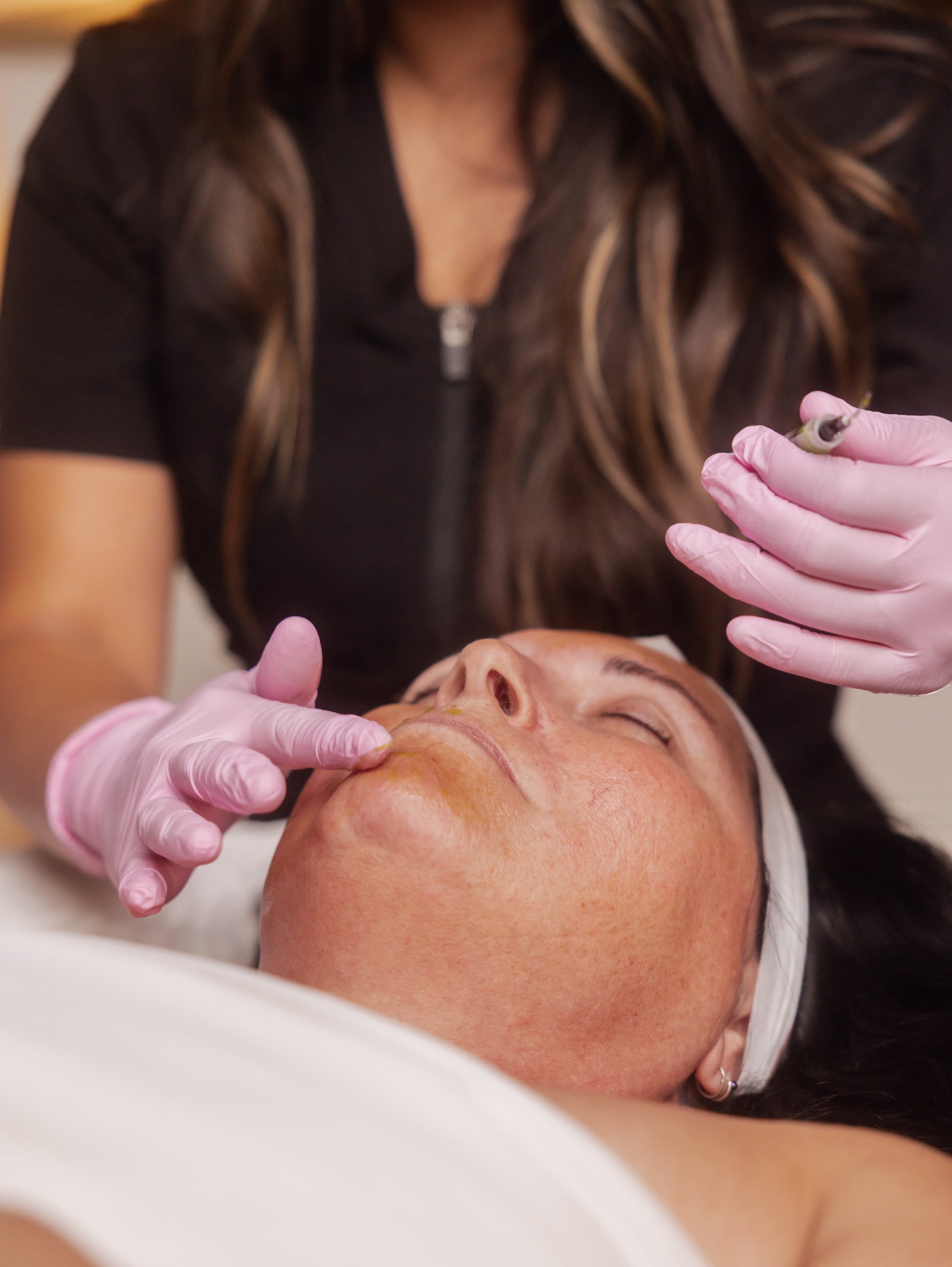 Esthetician performing a dermaplaning treatment on a client's cheek for smoother, brighter skin