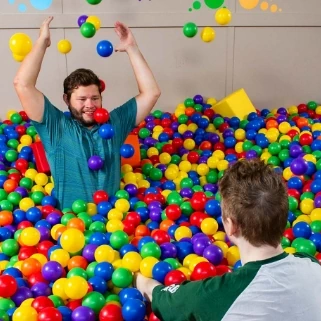 Residents playing in colorful ball pit at Flatrock sensory room, featuring fun therapy features like therapy balls for relaxation and engagement in autism support.