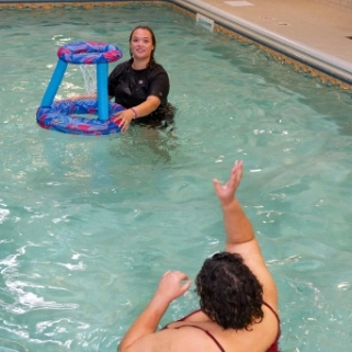 Residents playing water basketball in the indoor pool at Flatrock residences, fostering social connections and enjoyment in a family-oriented, supportive setting with private living quarters and recreation areas.