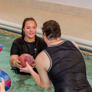 Residents engaging in fun water activities with an inflatable basketball hoop in the thoughtfully designed indoor pool at Flatrock residences, promoting connection, relaxation, and an inclusive supportive environment.