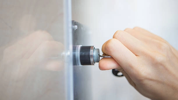 Hand inserting key into cylindrical lock on glass door