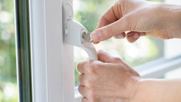 Hand inserting key into white window handle lock