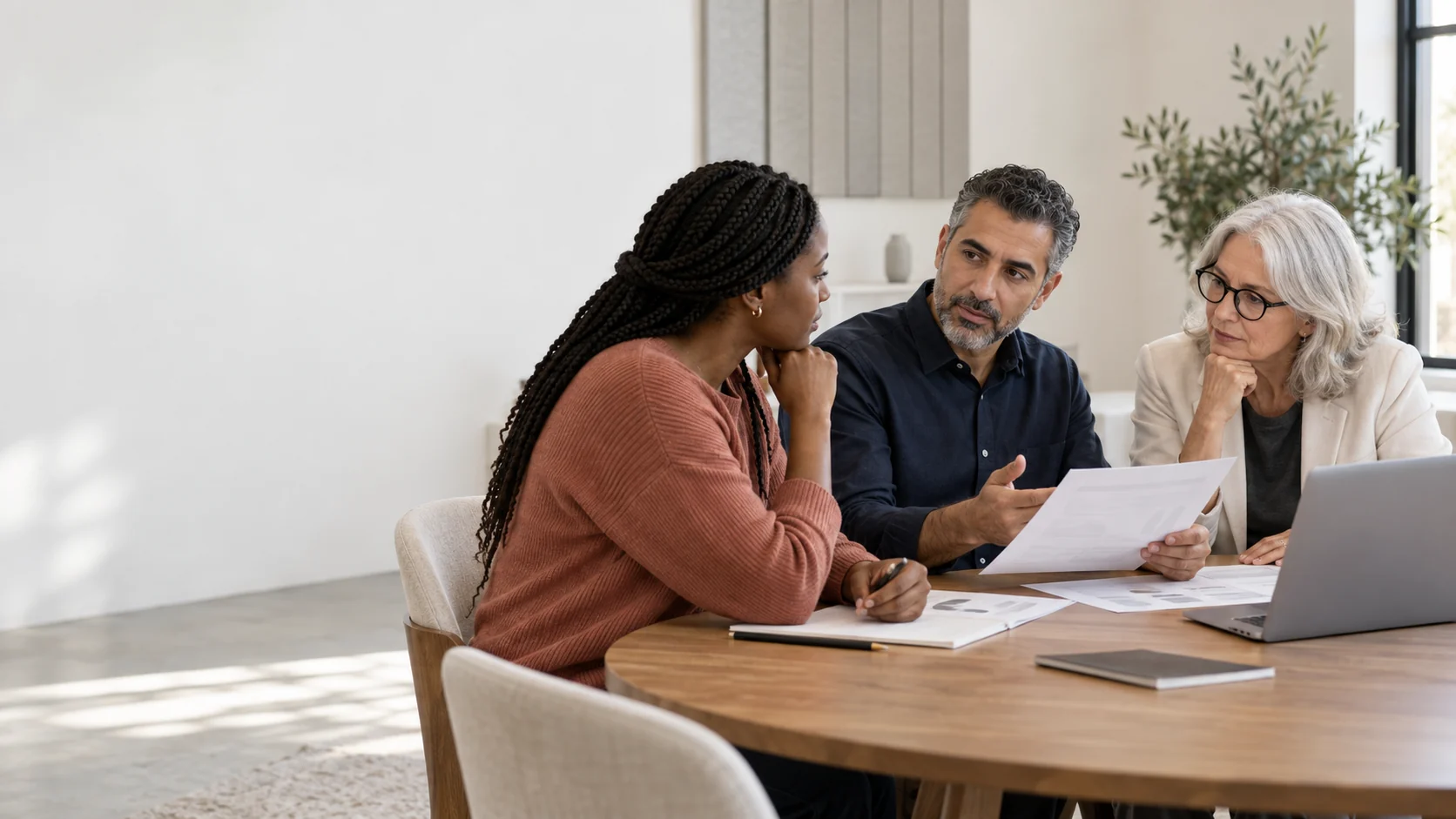 Three colleagues thoughtfully review evidence and discuss a decision around a shared table.