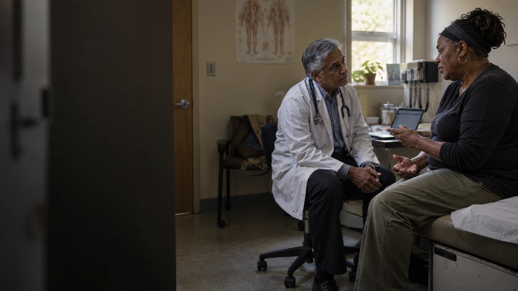 A physician listens at eye level to a patient in a community clinic