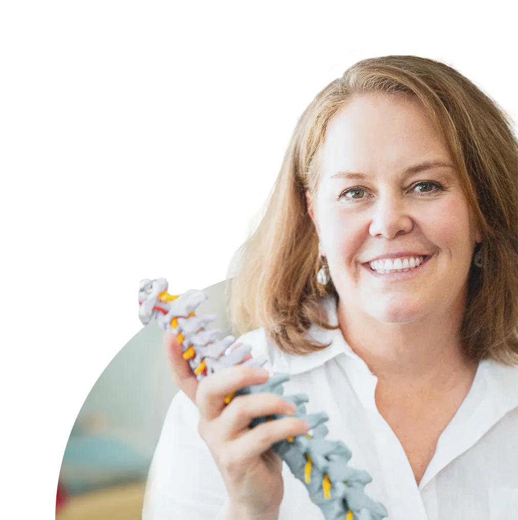 A smiling woman in a white shirt holding a model of a human spine, representing spinal health and wellness.
