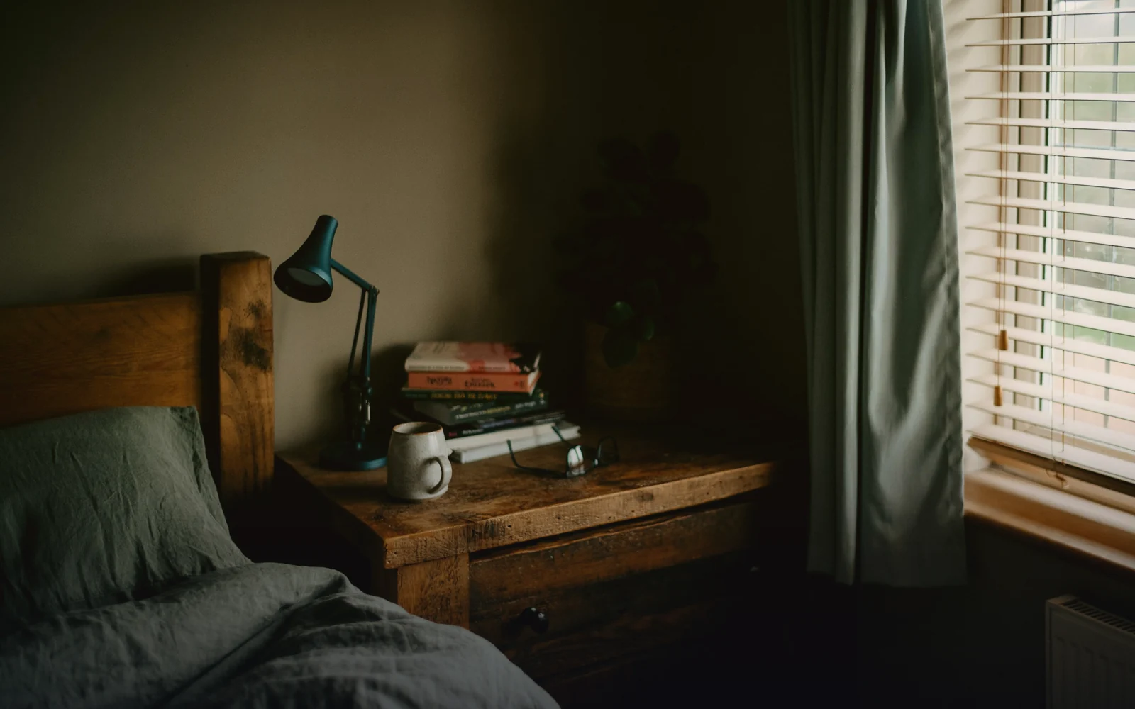 Cozy dim bedroom with a desk lamp and a mug, lofi mood