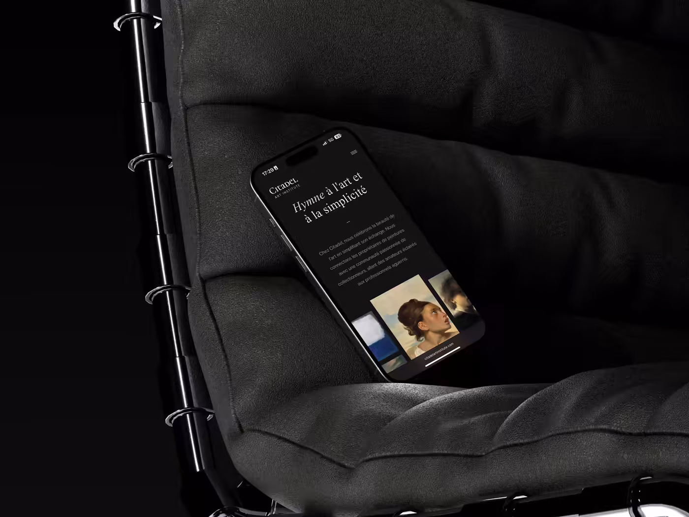 Smartphone placed on a dark armchair and displaying the Citadel Art Institute website.