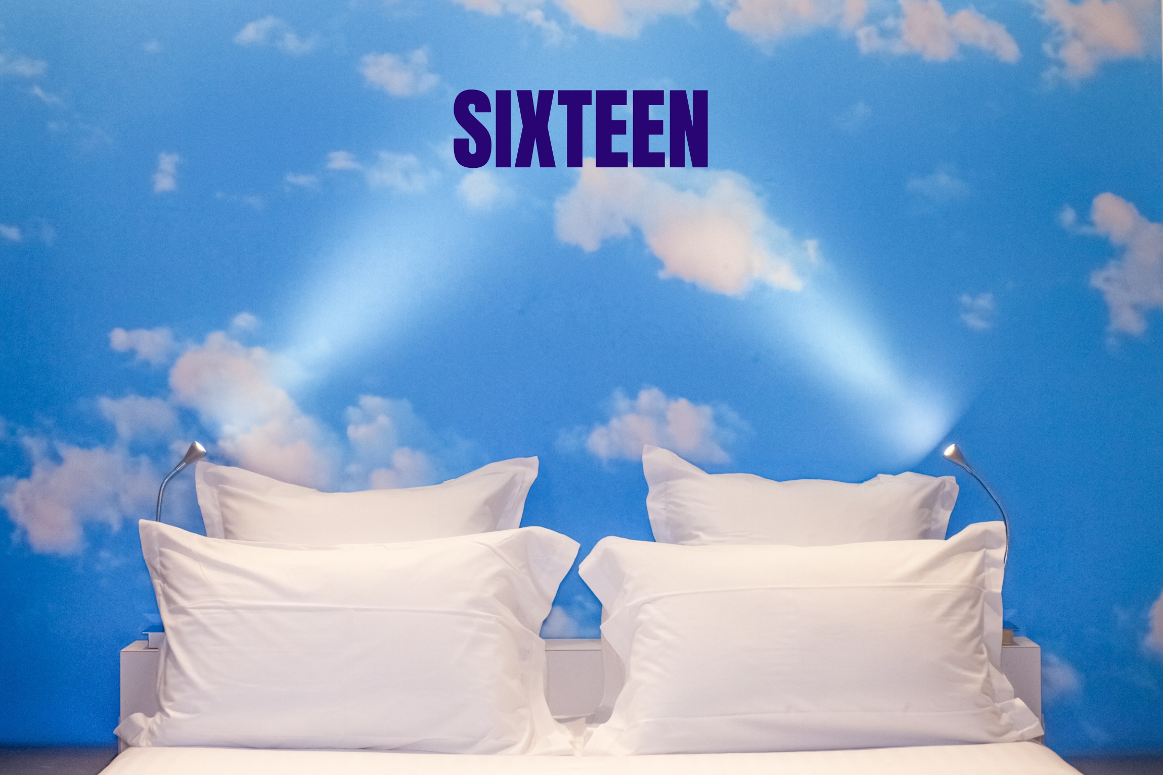 Guest room at Hôtel Sixteen, with white bed linen and a blue wall displaying the name Sixteen.
