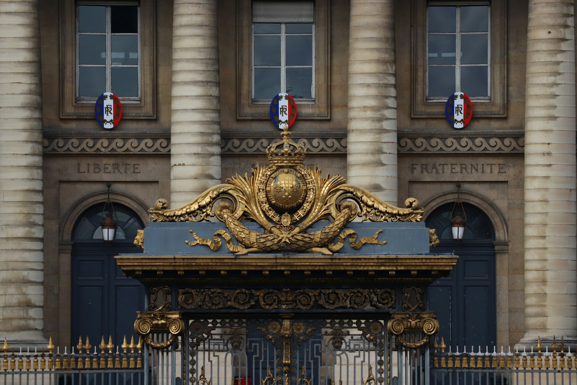 Monumental Parisian façade with columns, windows and gold ornamentation.