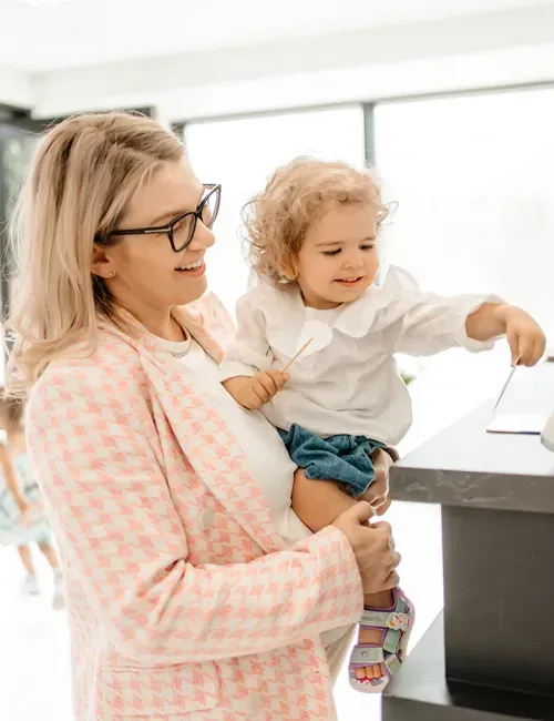 A parent and small child being welcomed at the My E20 Dentist reception desk