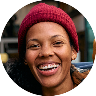 Smiling person wearing a burgundy knit beanie and black jacket