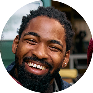 Smiling man with beard wearing earring and dark jacket against blurred background