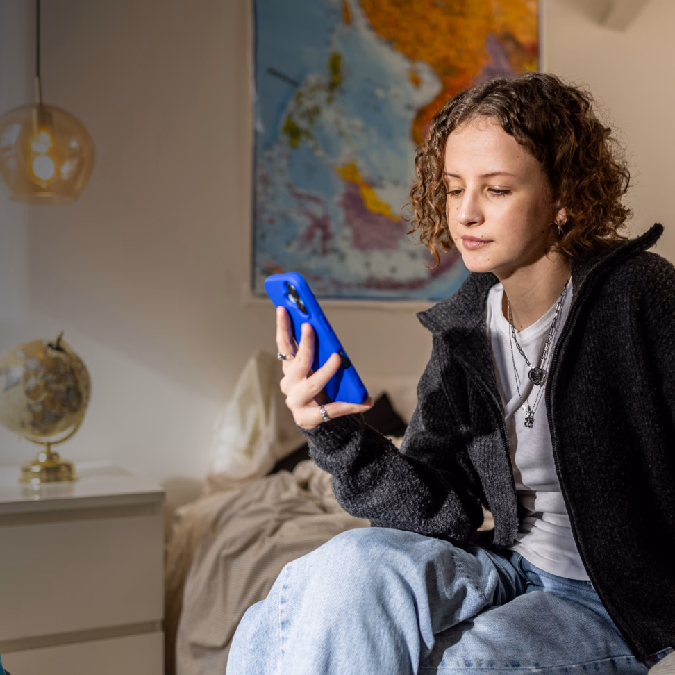 Woman using a savings app on her phone, showing €5,900 saved towards a €15,000 goal.