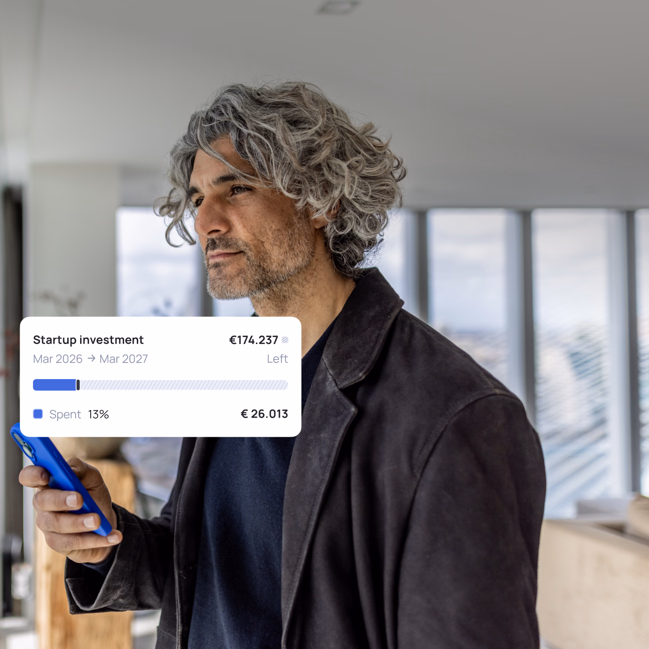 Man checking his phone while a finance app tracks progress towards a startup investment.