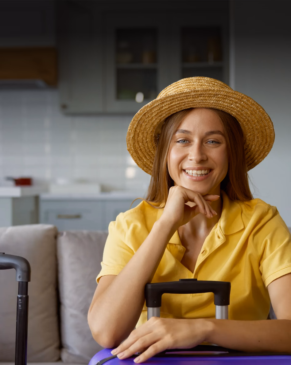 Smiling woman in yellow shirt and straw hat holding a purple loyalty card in a kitchen