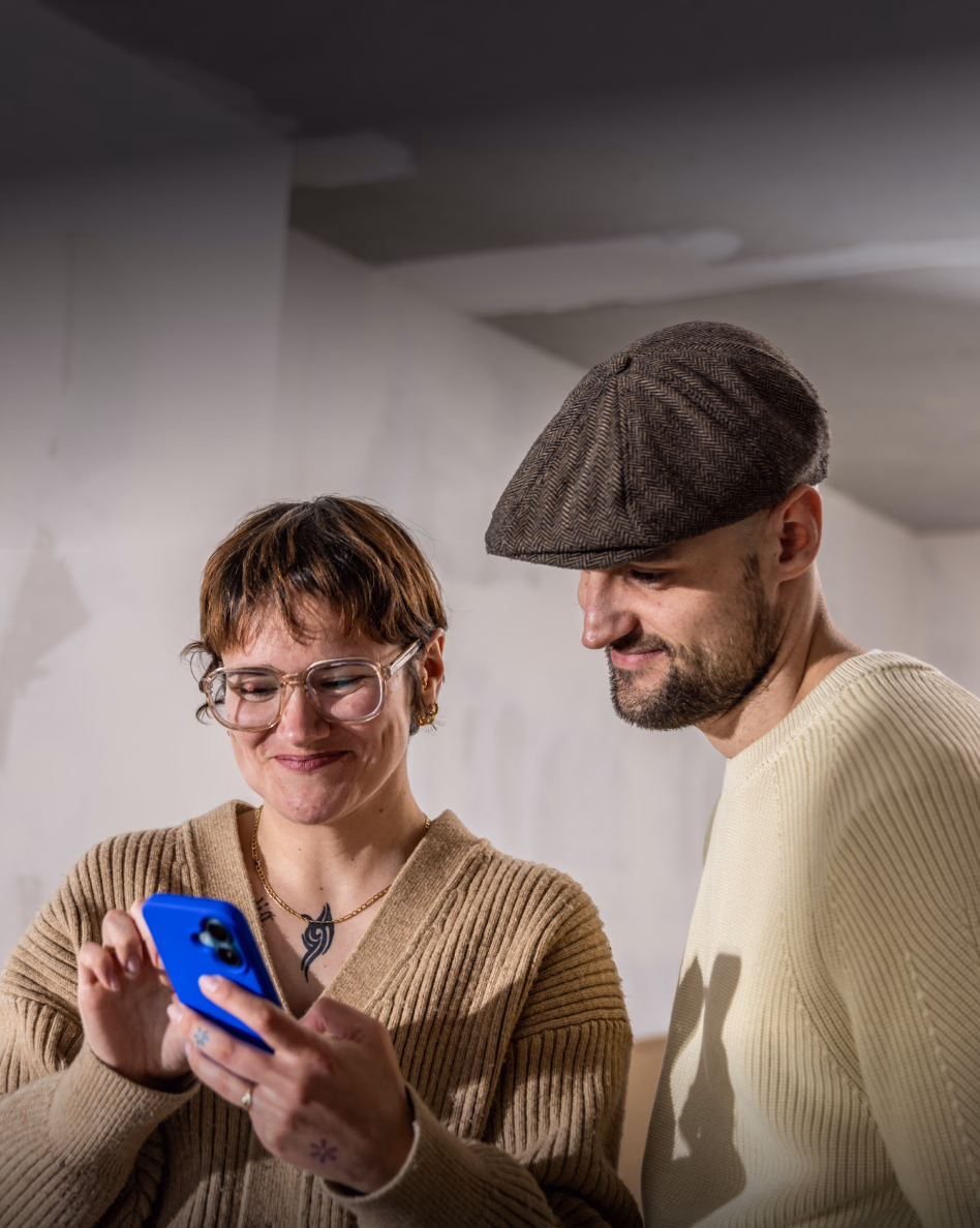 Two people looking at a blue smartphone together indoors
