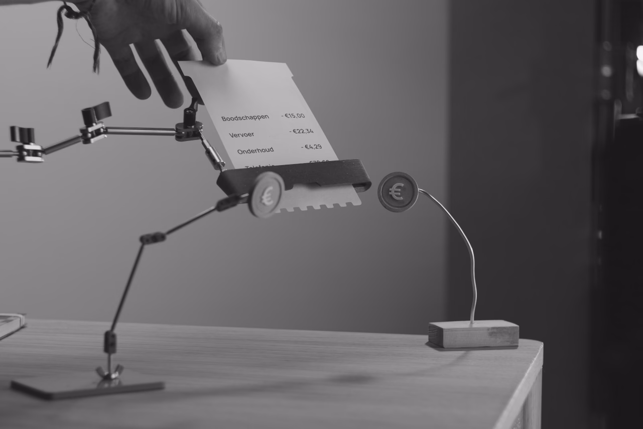 Hand holding a robotic device with articulated legs and a display screen showing text on a table