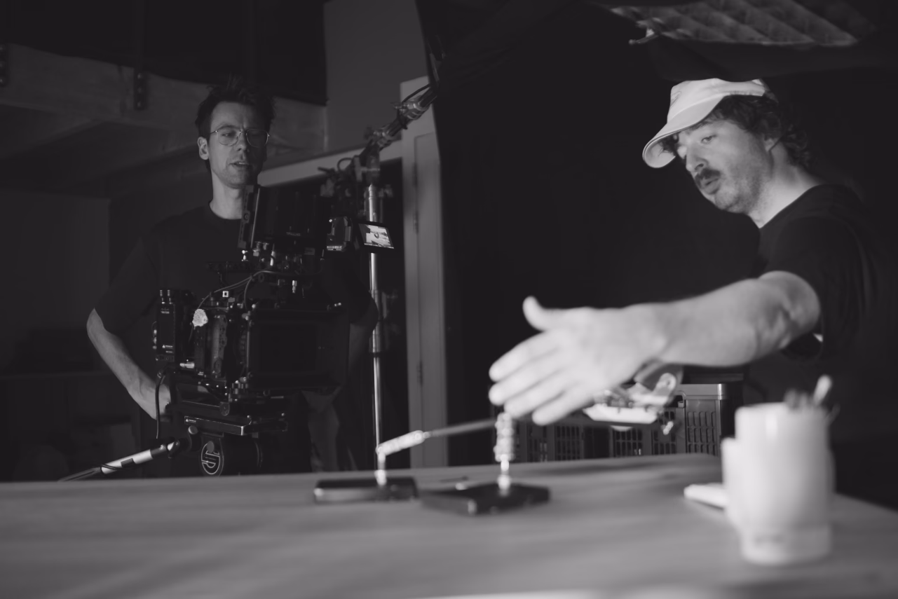Two men operating professional camera equipment in a studio setup with lighting rigs visible overhead