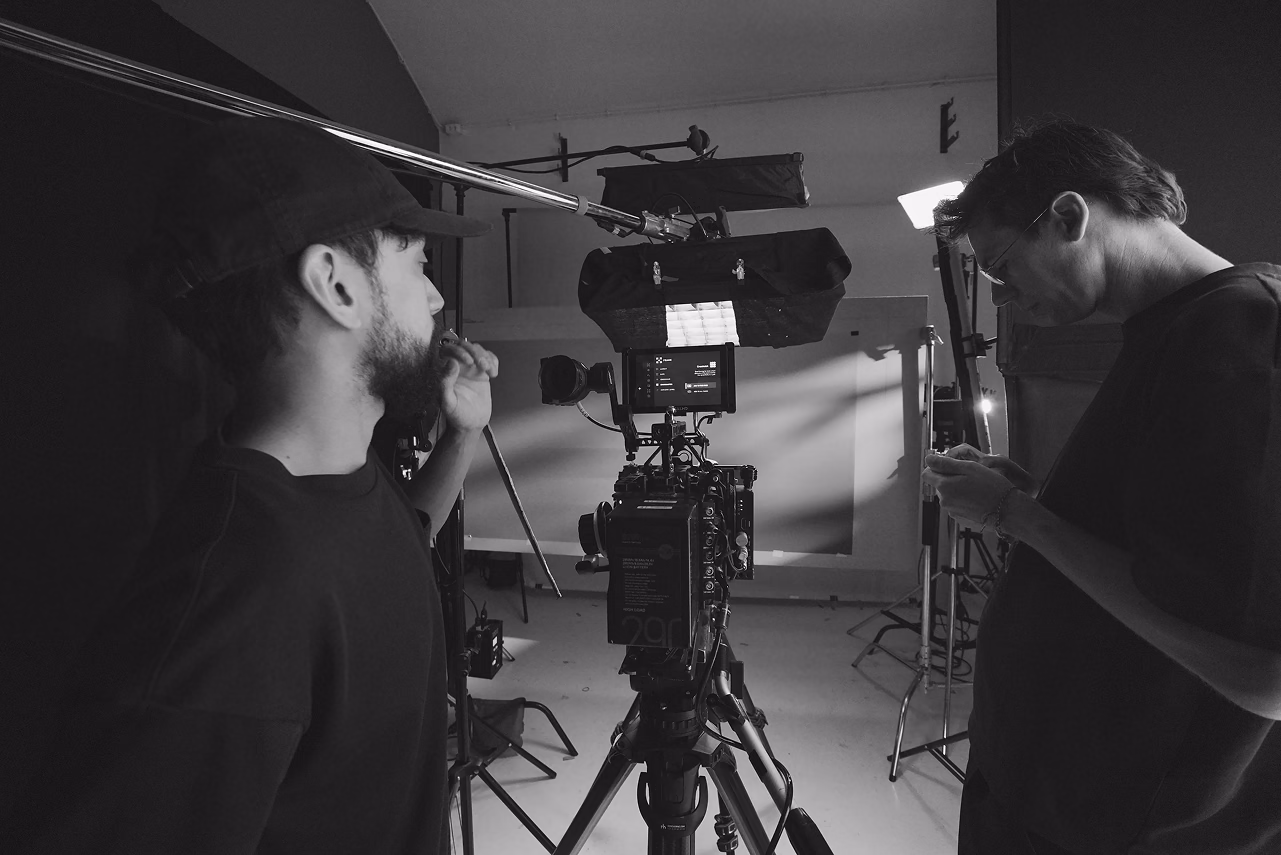Two men operating professional film camera equipment in a studio setting