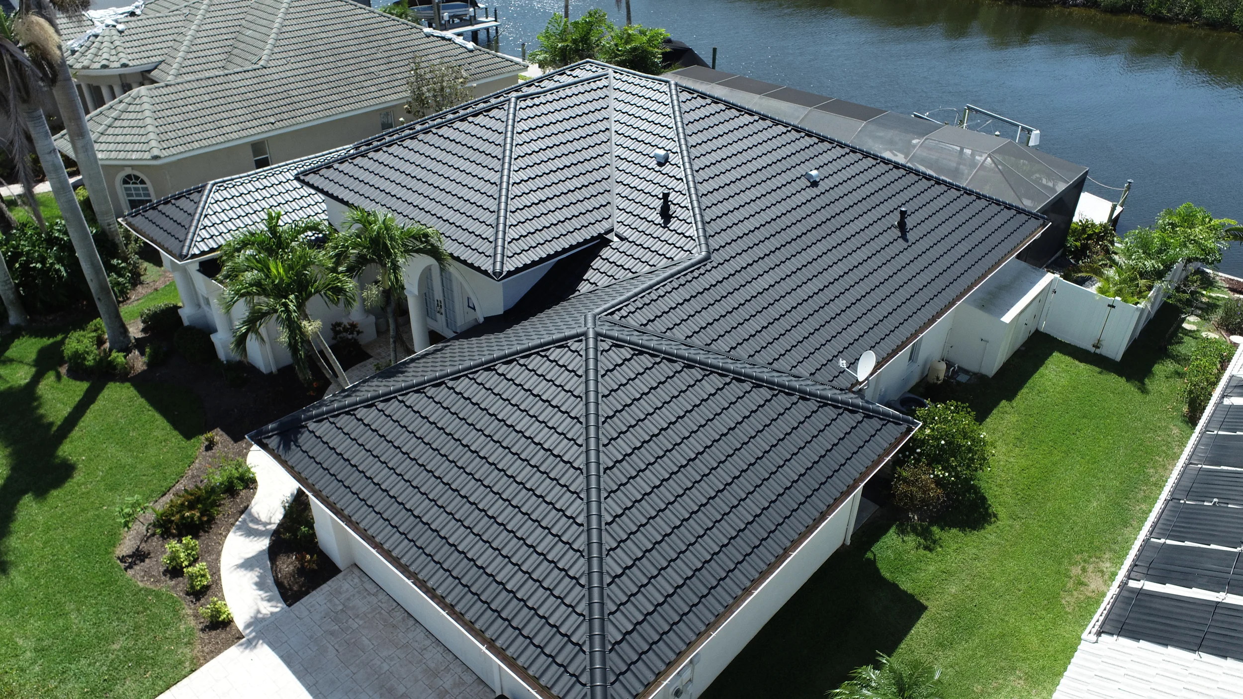 Aerial photo of the same white house with a gray metal tile roof.